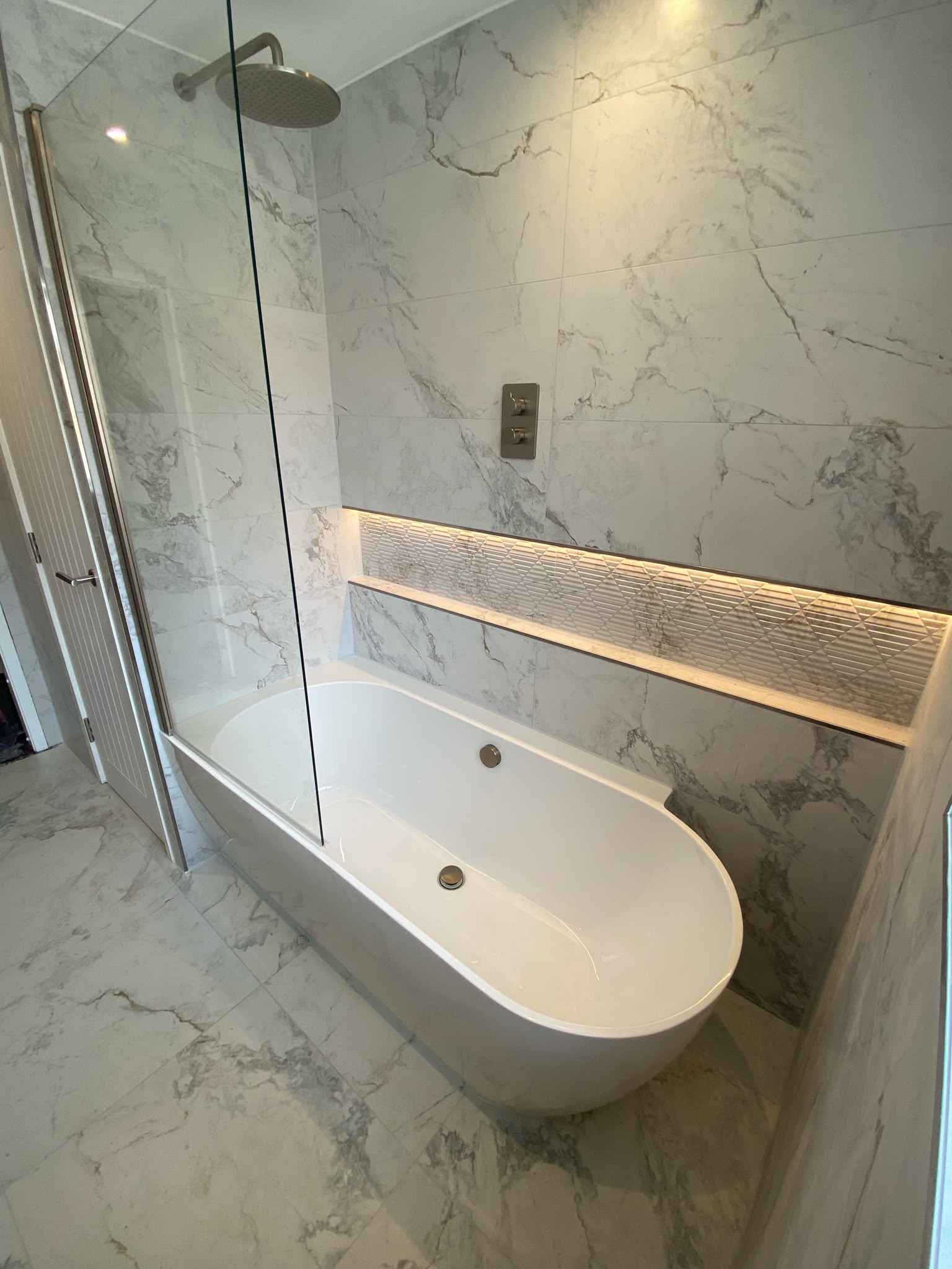 Modern semi freestanding bath with light up niche.