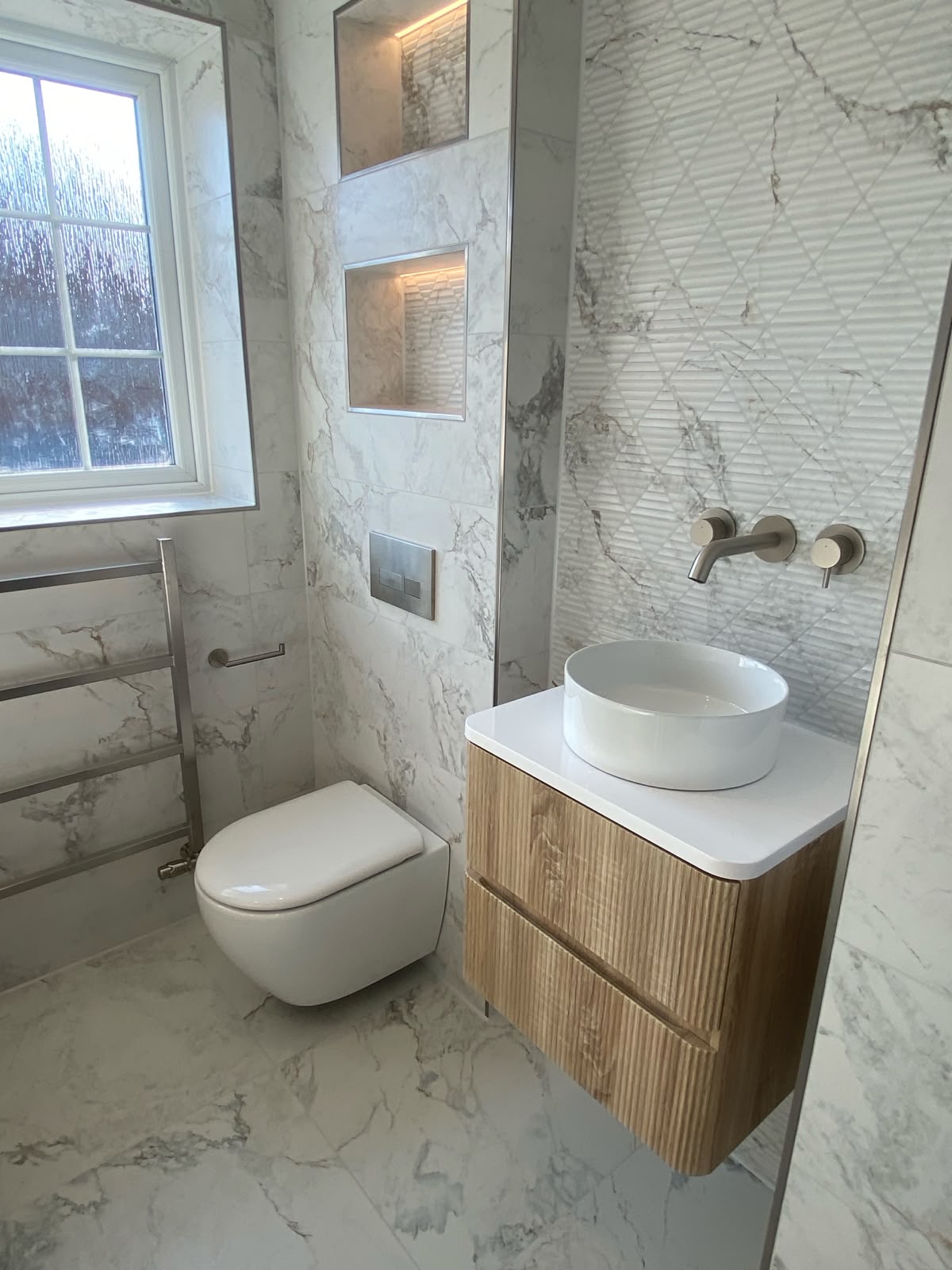 Wall hung toilet and basin with marble tiling.